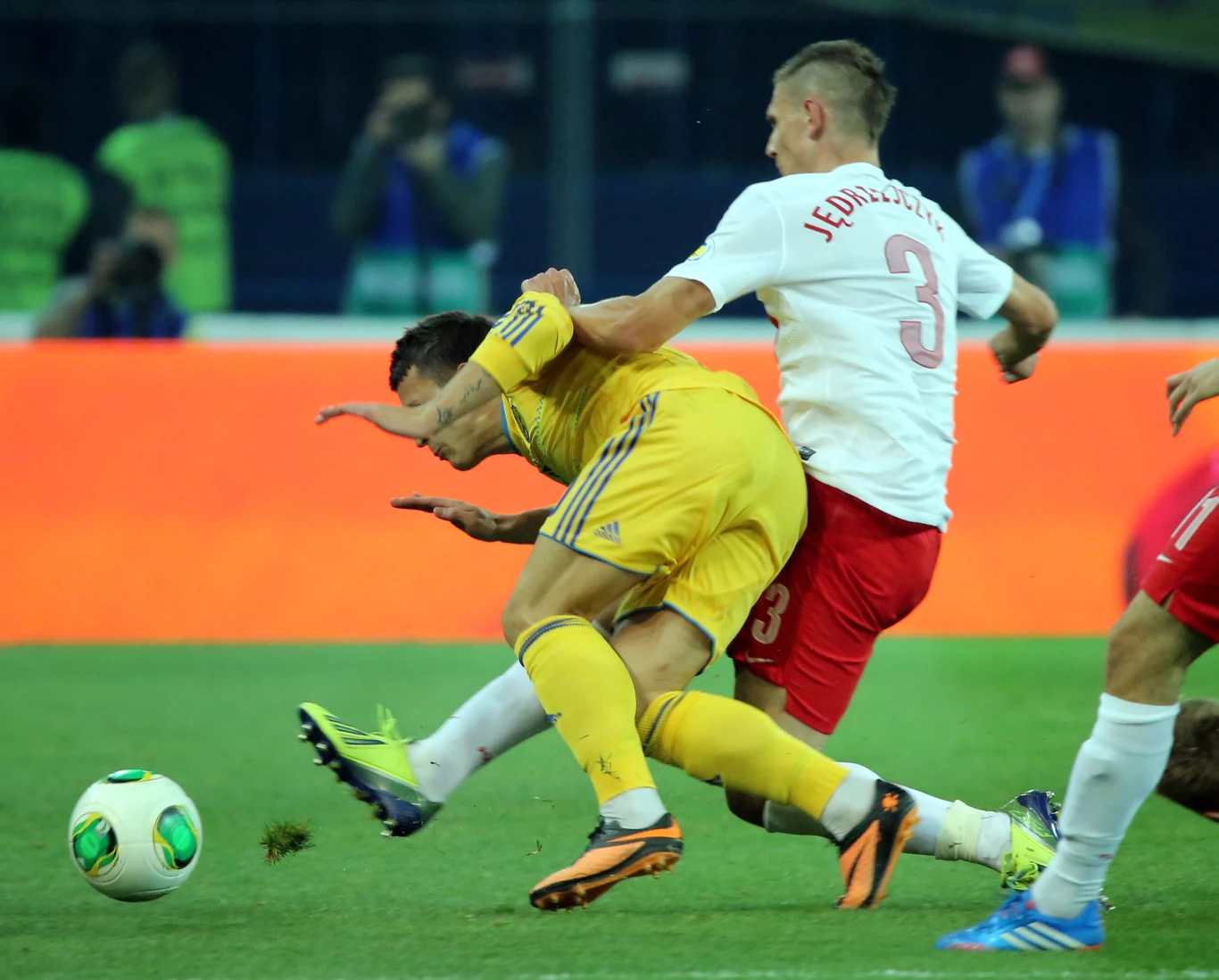 W starciu o piłkę gracz reprezentacji Polski Artur Jędrzejczyk (C) i Ukrainiec Jewhen Konopylanka