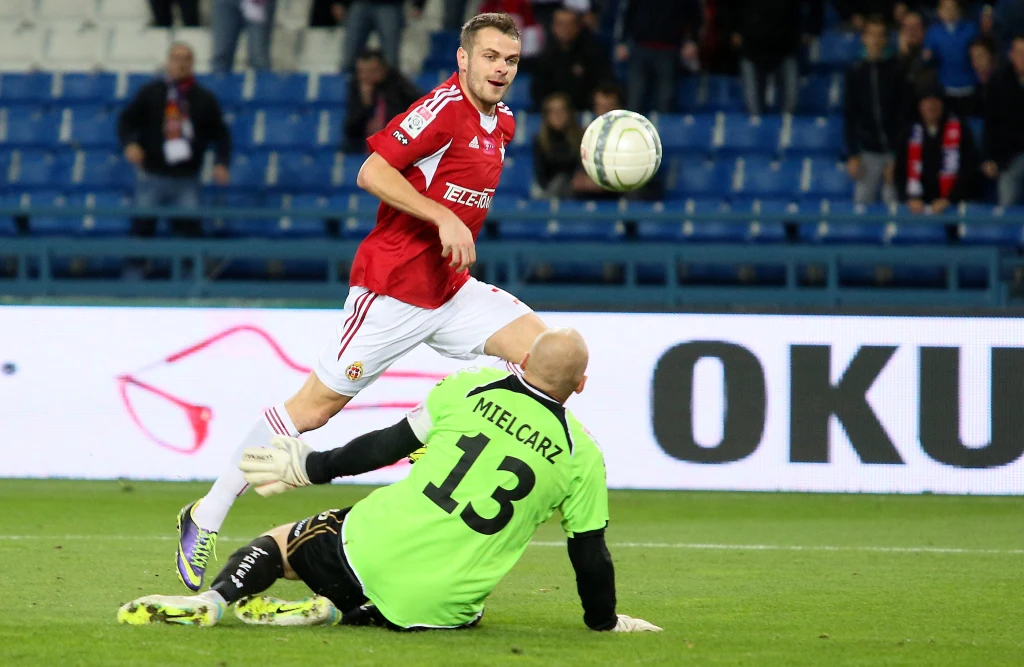 Piłkarz Wisły Kraków Paweł Brożek (z tyłu) pokonuje bramkarza Widzewa Łódź Macieja Mielcarza