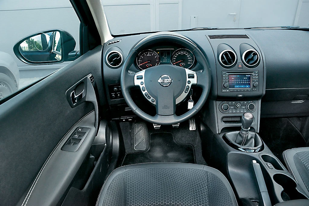 Nissan Qashqai 1.6 Acenta: morze ciemnego plastiku, ale porządnej jakości. Montaż jest staranny i nic nie trzeszczy na nierównościach. Panel seryjnej automatycznej klimatyzacji ma aż 11 niewielkich przycisków.