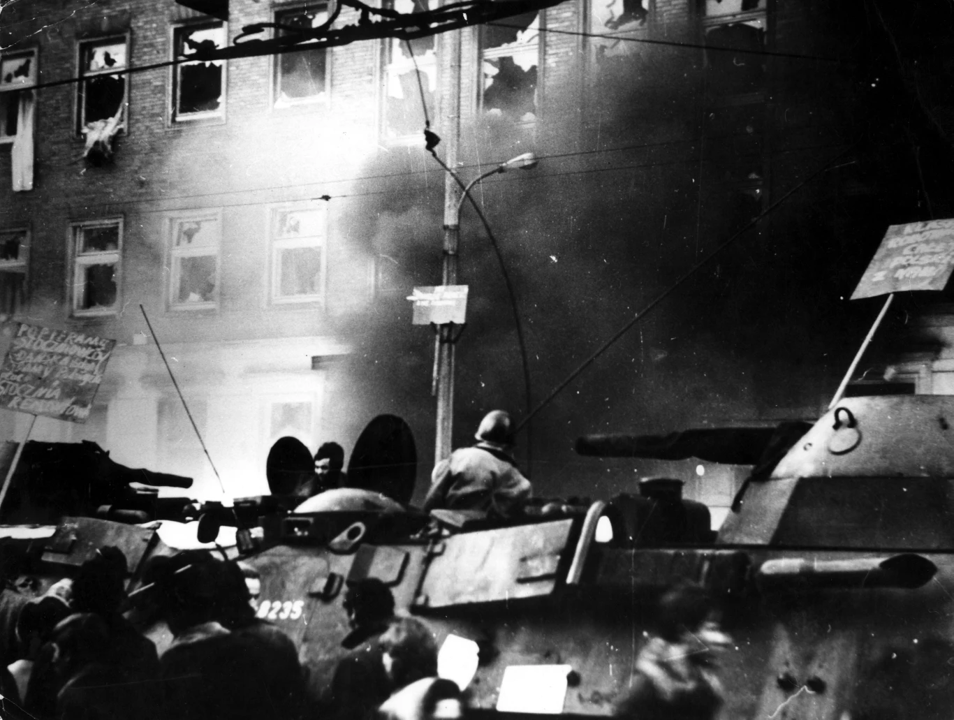 Szczecin, 17.12.1970, transportery opancerzone przed płonącym gmachem Komitetu Wojewódzkiego PZPR, napisy na transparentach: "Popieramy stoczniowców Gdańska (...) Stocznia Remontowa", "Klasa robotnicza całej Polski z nami!" Szczecin, 17.12.1970, transportery opancerzone przed płonącym gmachem Komitetu Wojewódzkiego PZPR, napisy na transparentach: "Popieramy stoczniowców Gdańska (...) Stocznia Remontowa", "Klasa robotnicza całej Polski z nami!"