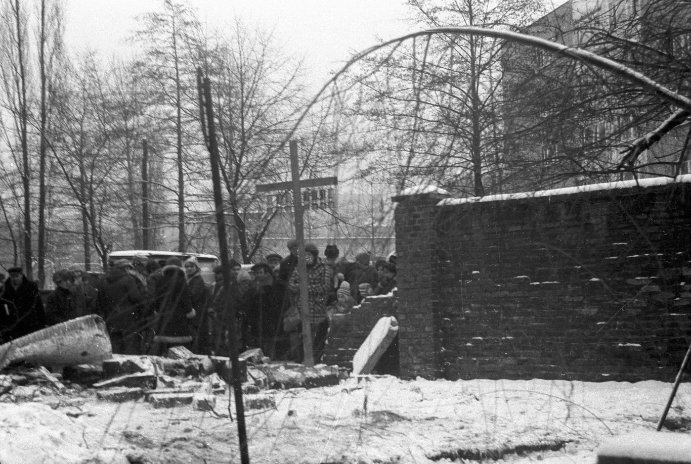 Wyrwa w murze wokół kopalni oraz krzyż postawiony dla upamiętnienia zabitych gorników. Zdjęcie zrobione następnego dnia po pacyfikacji, 17.12.1981