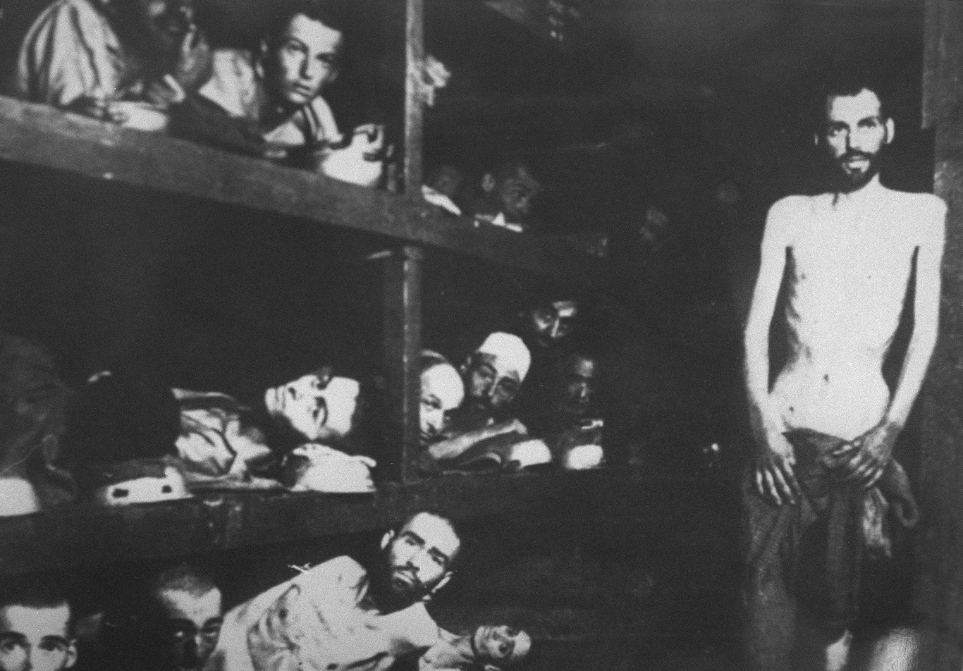 Żydowscy więźniowie w wyzwolonym obozie Auschwitz pozują do zdjęcia radzieckiemu żołnierzowi