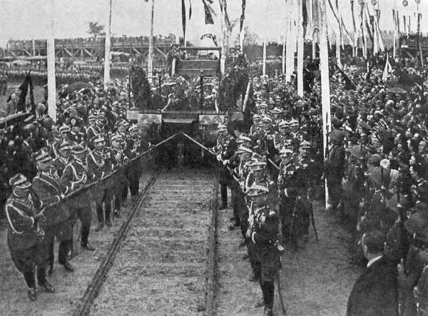 Generałowie Armii Polskiej przeciągają linami żałobny wagon z trumną Marszałka Piłsudskiego do oczekującego w pobliżu specjalnego pociągu, Pola Mokotowskie, Warszawa, 16.05.1935