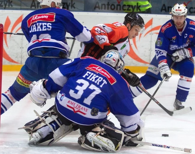 Hokeista JKH GKS Jastrzębie Damian Kapica (C) walczy o krążek z Tomaszem Jakeszem (L) i bramkarzem Michalem Fikrtem (P) z Aksam Unii Oświęcim