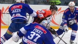 Hokeista JKH GKS Jastrzębie Damian Kapica (C) walczy o krążek z Tomaszem Jakeszem (L) i bramkarzem Michalem Fikrtem (P) z Aksam Unii Oświęcim