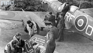 Lotnicy polskiego Dywizjonu 303 oglądają szczątki zestrzelonego samolotu niemieckiego "Ju 88". Z prawej widoczny samolot "Spitfire"