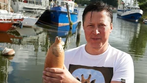 Archeolog podwodny z Narodowego Muzeum Morskiego w Gdańsku Tomasz Bednarz prezentuje ok. 200-letnią, oryginalnie zalakowaną kamionkową butelkę