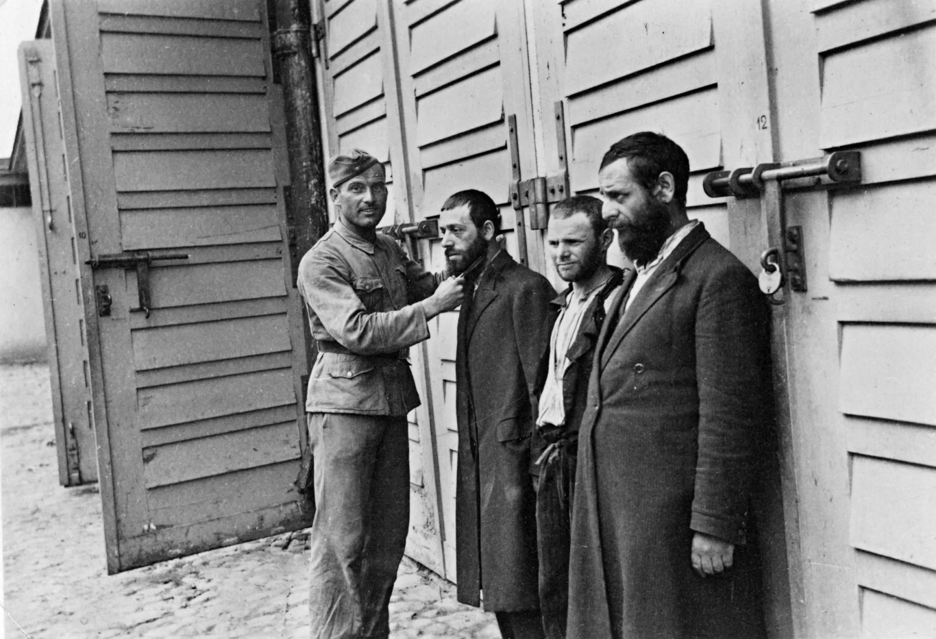 Żołnierz niemiecki ciągnie za brodę jednego z trzech zatrzymanych Żydow. Warszawa, 1939