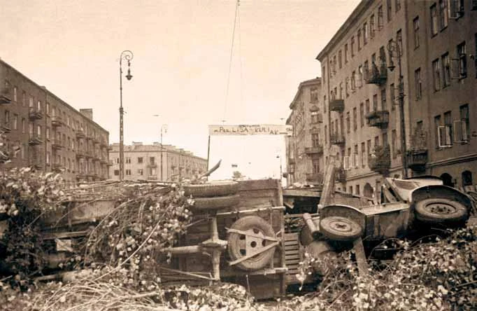 Barykada na ul. Okopowej przy skrzyżowaniu z ul. Żytnią na Woli. Widoczny transparent: „Barykada im. płk. Lisa- Kuli. AK, sierpień 1944”. Po prawej wylot ul. Kaczej i narożne kamienice przy ul. Okopowej 18 i 20. Barykada na ul. Okopowej przy skrzyżowaniu z ul. Żytnią na Woli. Widoczny transparent: „Barykada im. płk. Lisa- Kuli. AK, sierpień 1944”. Po prawej wylot ul. Kaczej i narożne kamienice przy ul. Okopowej 18 i 20.