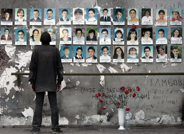 Ruiny szkoły w Biesłanie. Mężczyzna ogląda zdjęcia ofiar 