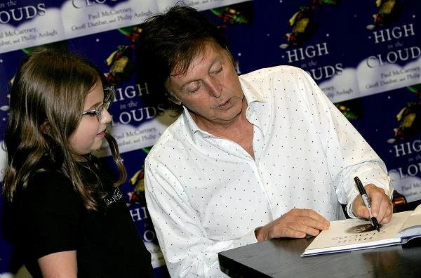 Paul z młodą fanką podpisuje swoją książkę dla dzieci
