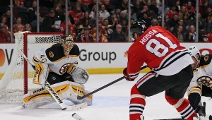 Tuukka Rask z Boston Bruins broni uderzenie Mariana Hossy z Chicago #81.