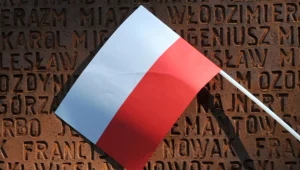 Polska flaga na tle pomnika pomordowanych przez Sowietów polskich oficerów w Charkowie