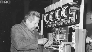 Robotnik podczas pracy przy rozdzielni elektrycznej. Widoczne gniazda bezpieczników i stos prostowniczy (zdjęcie ilustracyjne)