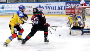 Hokeista GKS Tychy Jakub Witecki (C) pokonuje bramkarza Ondreja Raszkę (P) z TatrySki Podhale Nowy Targ