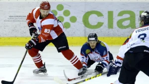 Hokeista Ciarko PBS Bank STS Sanok Alex Szczechura (w środku) walczy o krążek podczas meczu z Cracovią