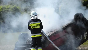 Strażak gasi płonący samochód (arch.)
