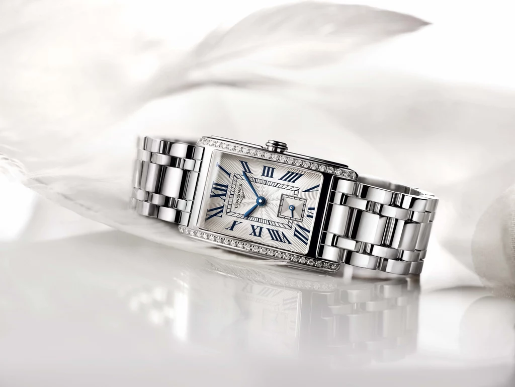 W hołdzie tym kobietom Longines stworzył interpretację swojej kolekcji, subtelnie łączącą geometryczne kształty z miękkimi łukami. Linie prostokątnej koperty zostały wysmuklone i zaokrąglone. W hołdzie tym kobietom Longines stworzył interpretację swojej kolekcji, subtelnie łączącą geometryczne kształty z miękkimi łukami. Linie prostokątnej koperty zostały wysmuklone i zaokrąglone.
