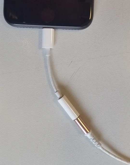 Przewodowe słuchawki podłączone do iPhone'a przez przejściówkę Przewodowe słuchawki podłączone do iPhone'a przez przejściówkę