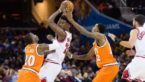 Jimmy Butler (z piłką) w walce z koszykarzami Cleveland Cavaliers