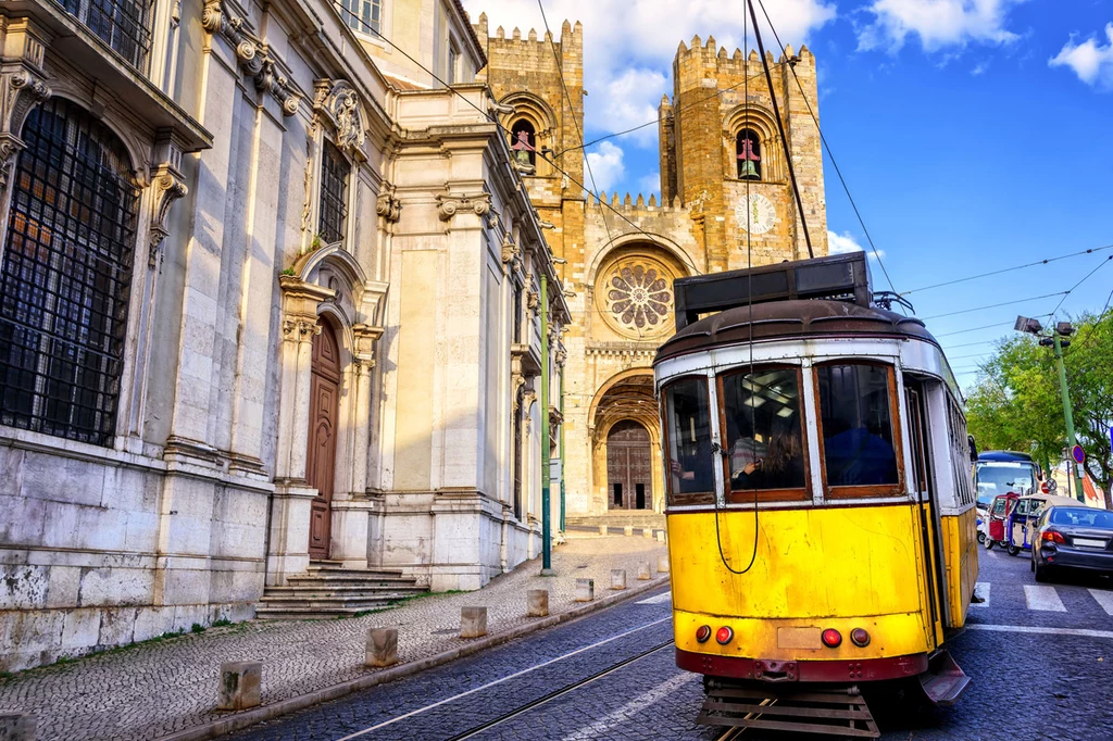 Historyczny żółty tramwaj naprzeciwko katedry z Lizbony