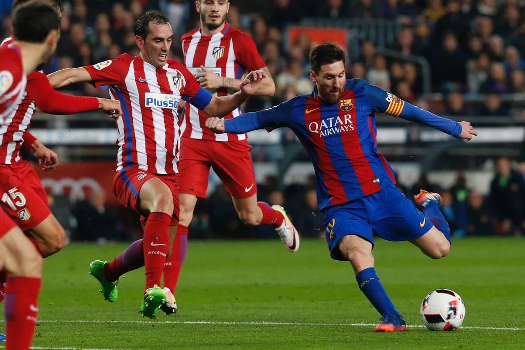 Lionel Messi (z prawej) walczy z Diego Godinem podczas półfinałowego boju z Atletico