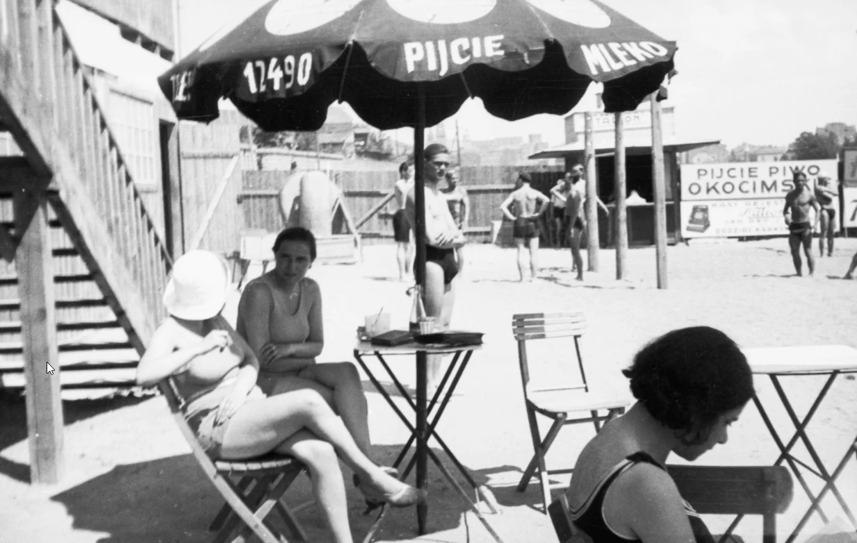 Plażowicze w Krakowie podczas wypoczynku pod parasolem z napisem "Pijcie mleko". W tle widoczna reklama z napisem "Pijcie piwo Okocimskie" (zdjęcie z 1931 roku)