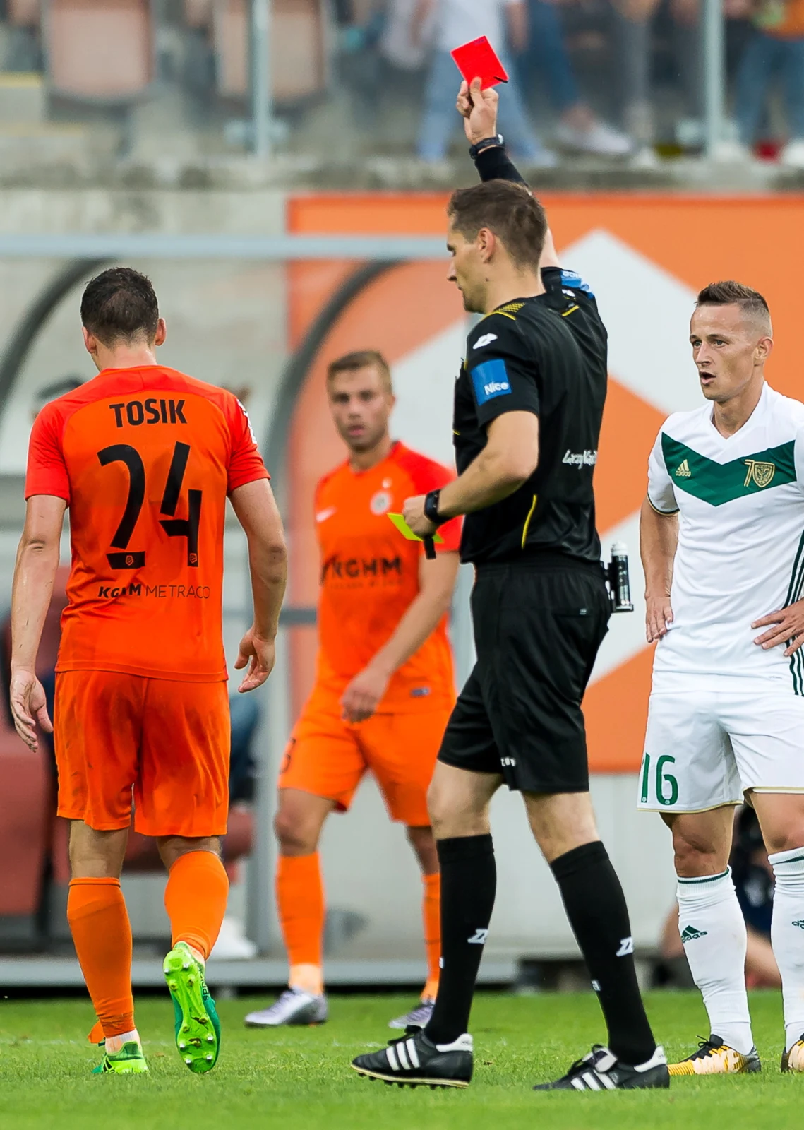 Sędzia Tomasz Kwiatkowski (C) pokazuje czerwoną kartkę Jakubowi Tosikowi (L) z Zagłębia Lubin