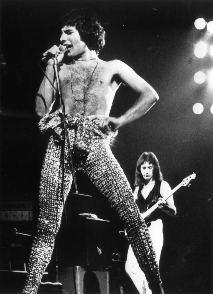 Freddie Mercury w 1977 r. W tle basista Queen John Deacon