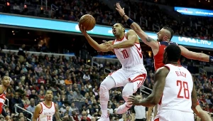 Eric Gordon #10 z Houston Rockets szykuje się do rzutu, a Marcin Gortat #13 z Washington Wizards próbuje go zablokować.