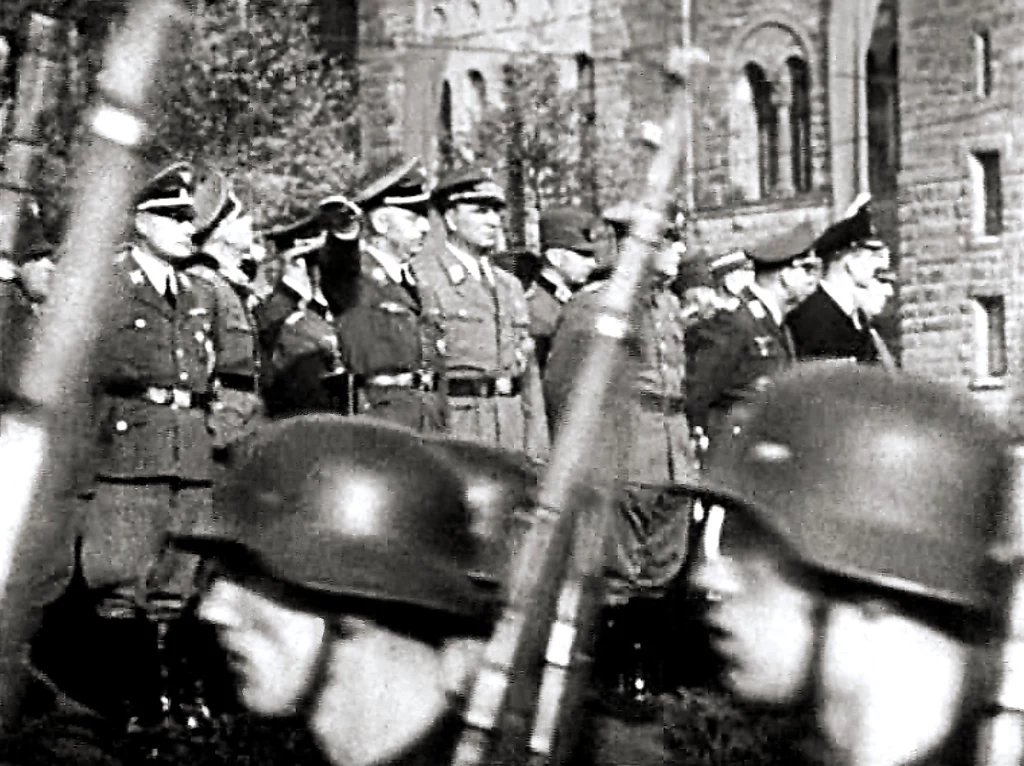 Kadr z hitlerowskiej kroniki filmowej „Die Deutsche Wochenschau” z reportażem z obchodów Dnia Wolności w Posen. Na trybunie obok zamku poznańskiego stoi obergruppenführer SS Wilhelm Koppe (pierwszy z lewej). Defiladę odbiera reichsführer SS Heinrich Himmler Kadr z hitlerowskiej kroniki filmowej „Die Deutsche Wochenschau” z reportażem z obchodów Dnia Wolności w Posen. Na trybunie obok zamku poznańskiego stoi obergruppenführer SS Wilhelm Koppe (pierwszy z lewej). Defiladę odbiera reichsführer SS Heinrich Himmler