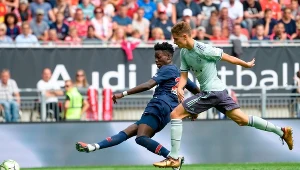 Młody piłkarz PSG - Timothy Weah (z lewej) strzela gola mimo presji ze strony Josipa Staniszicia