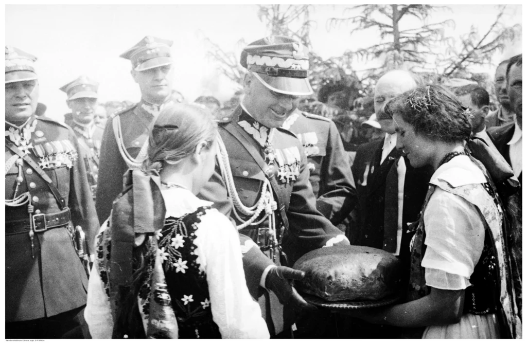 Uroczystości ku czci Michała Pyrza w Nowosielcach. Generał Edward Rydz-Śmigły odbiera bochen chleba z rąk dziewcząt ubranych w stroje regionalne. Za E. Rydzem-Śmigłym widoczni m.in. generał Wacław Scewola-Wieczorkiewicz i pułkownik Leon Strzelecki Uroczystości ku czci Michała Pyrza w Nowosielcach. Generał Edward Rydz-Śmigły odbiera bochen chleba z rąk dziewcząt ubranych w stroje regionalne. Za E. Rydzem-Śmigłym widoczni m.in. generał Wacław Scewola-Wieczorkiewicz i pułkownik Leon Strzelecki