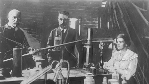 Maria Skłodowska-Curie i jej mąż Pierre (w środku) w laboratorium (fotografia oryginalna wykonana przed 1906 rokiem, która znalazła się w zasobie "Ilustrowanego Kuriera Codziennego"