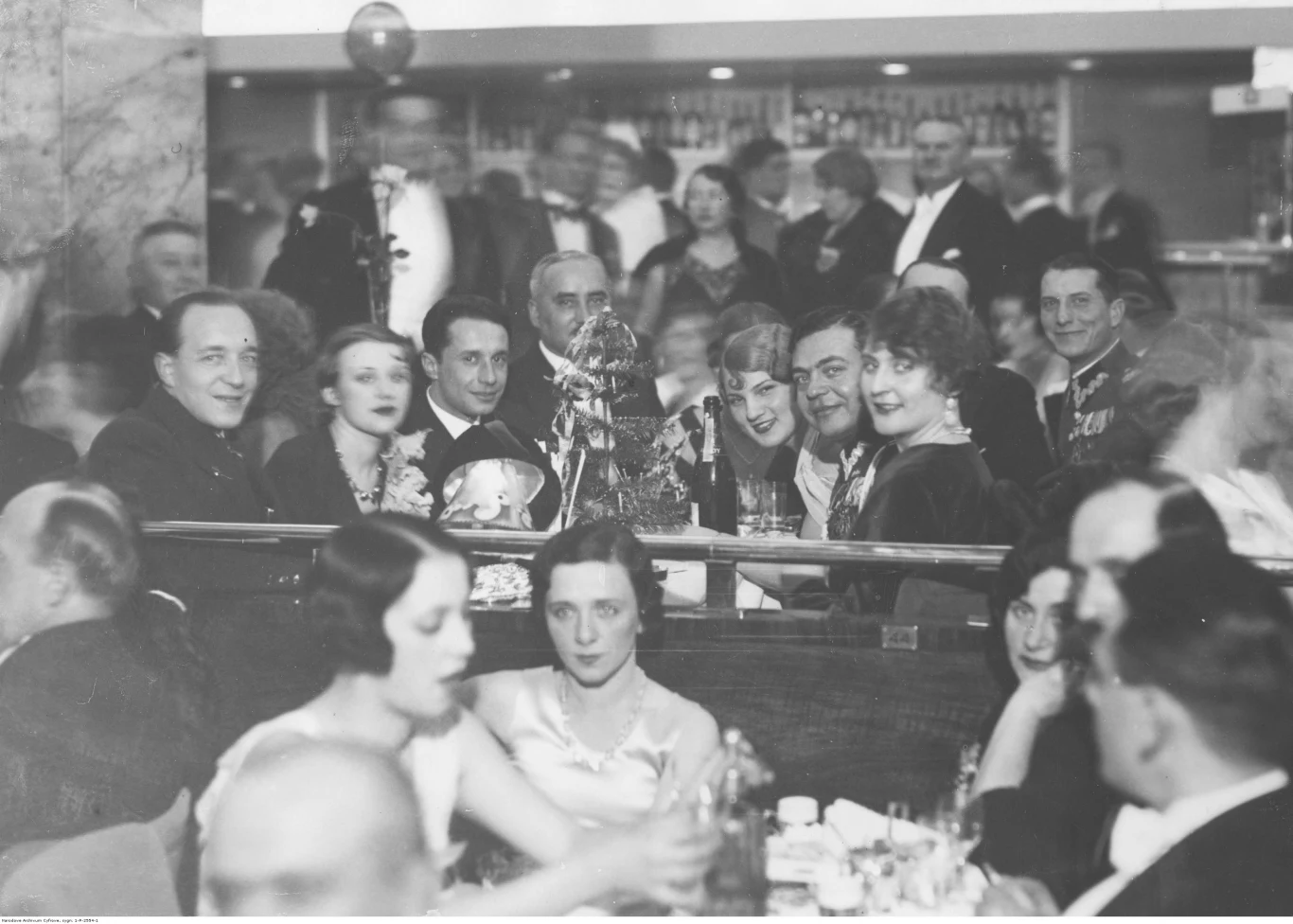 Bal sylwestrowy w lokalu Adria w Warszawie. Uczestnicy balu przy stolikach. Widoczni m.in.: mjr Edward Czuruk (na drugim planie przy stole, siedzi 3. z prawej) i mjr Wiktor Gębalski (w głębi z prawej)
