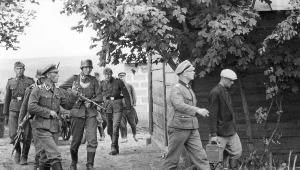 Żołnierze i żandarmi niemieccy podczas przeszukiwania wiejskich zabudowań w czasie wojny (zdjęcie ilustracyjne)