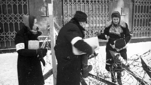 Dwoje Żydów przechodzi przez zasieki z drutów kolczastych w getcie w Warszawie