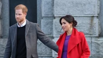 W Birkenhead Meghan pojwiła się  w czerwonym płaszczu Sentaler i fioletowej sukience  Aritzia. 