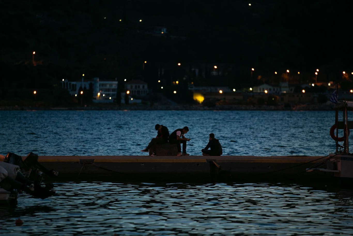 Grupa uchodźców z Afganistanu podczas nocnych rozmów w porcie Vathy