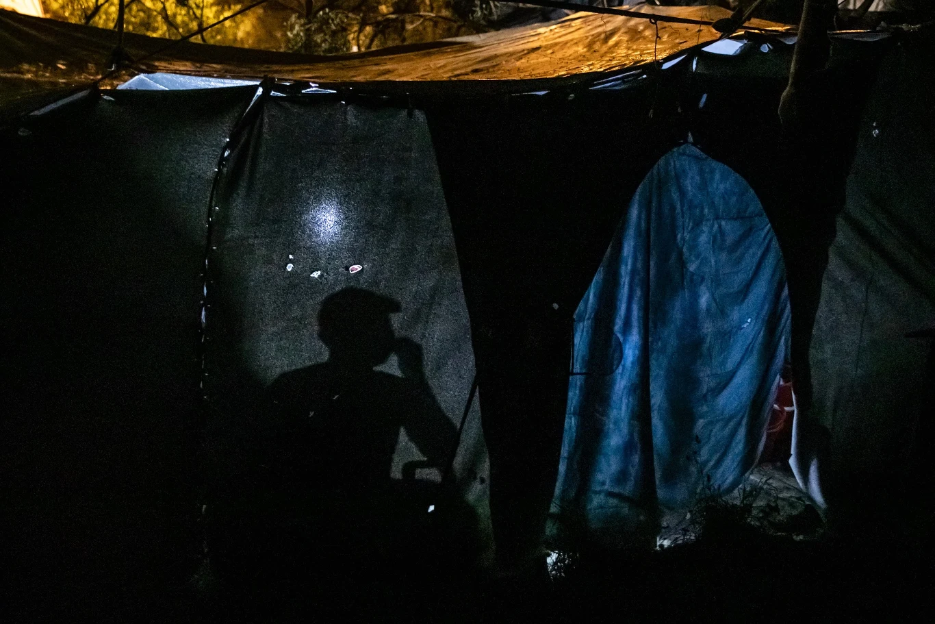 Cień mężczyzny siedzącego nocą w namiocie obozu dla uchodźców