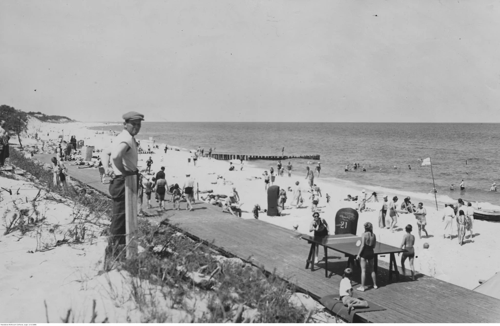 Plażowicze podczas wypoczynku. Widoczny drewniany deptak, wiklinowe kosze plażowe oraz stół do ping-ponga w Juracie, lata 1918–1937. Fot. Narodowe Archiwum Cyfrowe