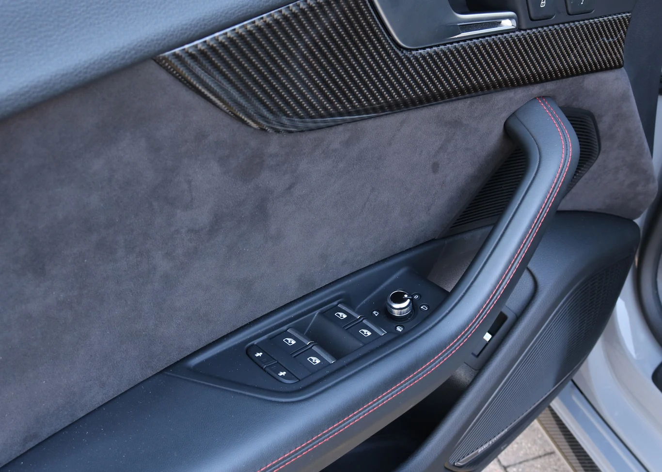 Typowo dla nowych modeli Audi - pomimo skórzanej tapicerki, boczki drzwi pozostają wykończone alcantarą. Tylko podłokietnik i uchwyt korespondują z wybraną tapicerką siedzeń.