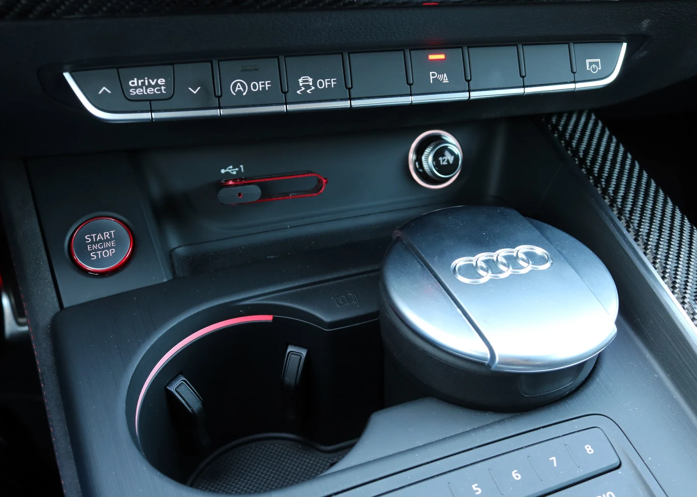 Niezbyt wygodnie korzysta się z tych przełączników (szczególnie z małych strzałek do wyboru trybu jazdy), a przycisk Start umieszczono za daleko. Stylowa popielniczka.