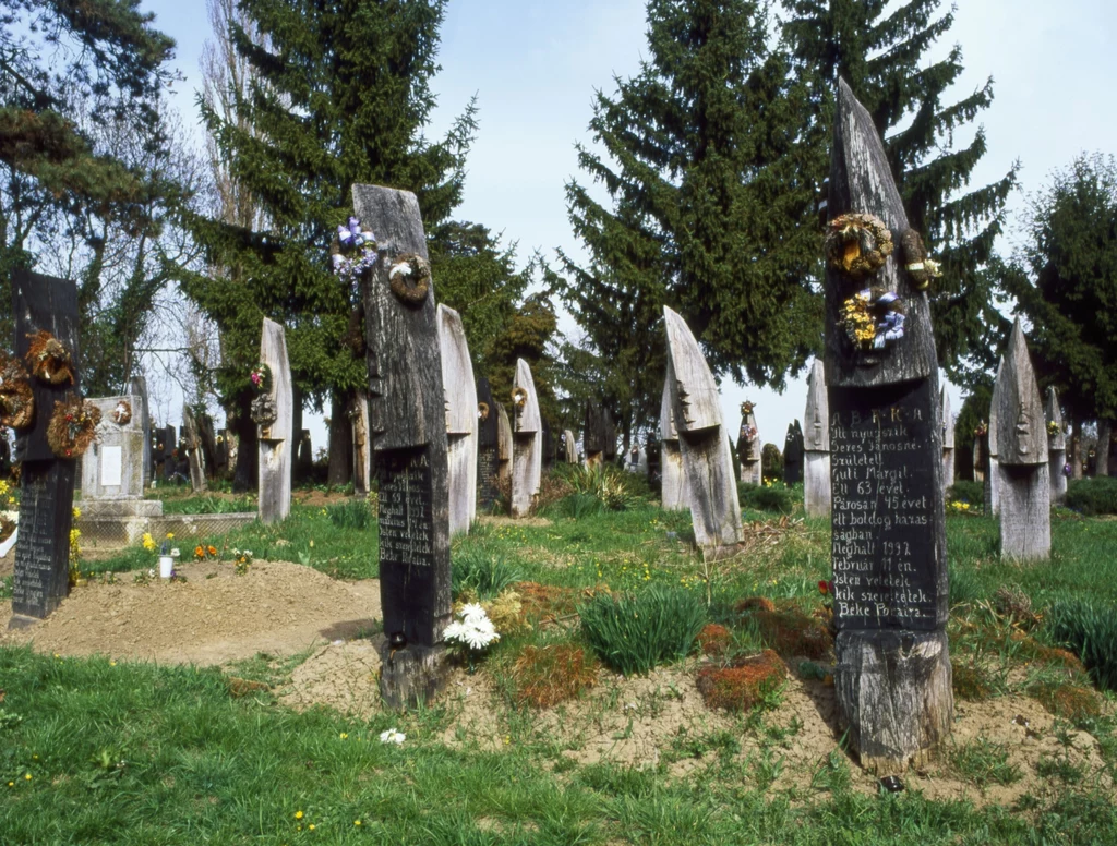 Cmentarz w Szatmarcseke (Węgry) Kalwiński cmentarz, który słynie z drewnianych nagrobków w kształcie wąskich czółen wbitych pionowo w ziemię. Najstarsze pochodzą z XVIII w., a zmarłych do dziś chowa się w ten nietypowy sposób. Czółna symbolizują wędrówkę do innego świata. Wszystkie nagrobki są ustawione w tym samym kierunku, wiele jest bogato zdobionych, a z ich kształtu i nacięć można odczytać informacje o zmarłych. Cmentarz w Szatmarcseke (Węgry) Kalwiński cmentarz, który słynie z drewnianych nagrobków w kształcie wąskich czółen wbitych pionowo w ziemię. Najstarsze pochodzą z XVIII w., a zmarłych do dziś chowa się w ten nietypowy sposób. Czółna symbolizują wędrówkę do innego świata. Wszystkie nagrobki są ustawione w tym samym kierunku, wiele jest bogato zdobionych, a z ich kształtu i nacięć można odczytać informacje o zmarłych.