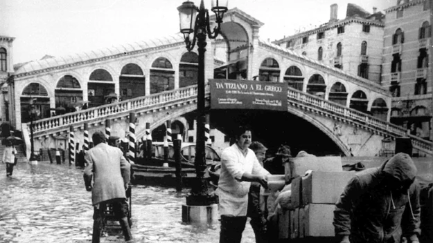 Pracownicy pobliskich hoteli próbują zabezpieczyć bagaże swoich gości. W tle słynny most Rialto. Wenecja, 1981 rok. 