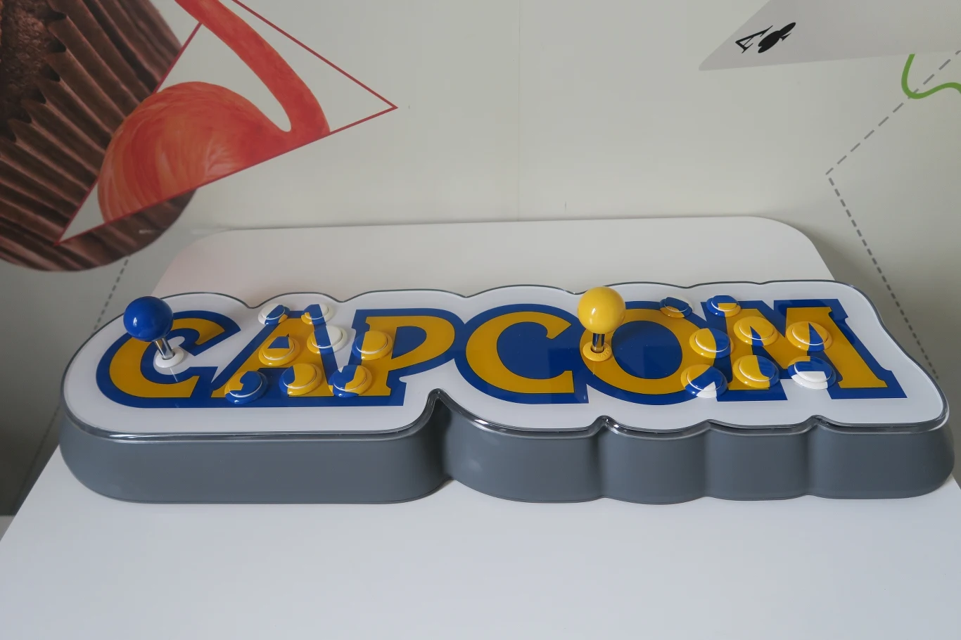 W pudełku znajdziemy kontroler i konsolę w jednym, czyli tytułowy Capcom Home Arcade. Sprzęt od razu rzuca się w oczy – to mająca wymiary 14 na 77 na 24 cm rekonstrukcja logo firmy Capcom z dwoma kontrolerami i 8 przyciskami po każdej ze stron. Całość prezentuje się – delikatnie mówiąc – kuriozalnie, ale została wykonana na najwyższym poziomie. W pudełku znajdziemy kontroler i konsolę w jednym, czyli tytułowy Capcom Home Arcade. Sprzęt od razu rzuca się w oczy – to mająca wymiary 14 na 77 na 24 cm rekonstrukcja logo firmy Capcom z dwoma kontrolerami i 8 przyciskami po każdej ze stron. Całość prezentuje się – delikatnie mówiąc – kuriozalnie, ale została wykonana na najwyższym poziomie.