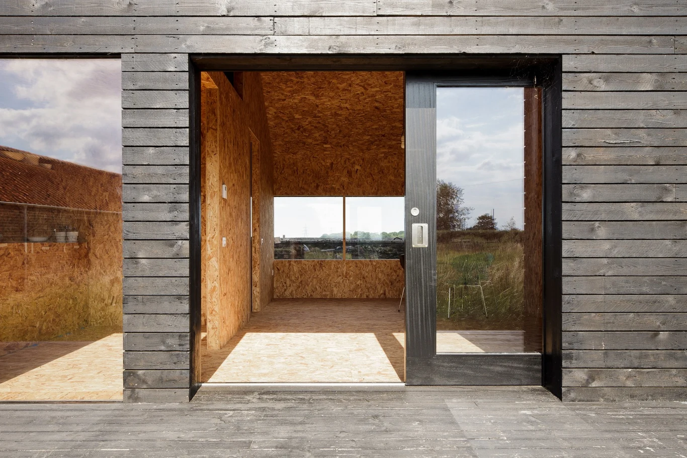 Z zewnątrz budynek obłożono szorstkimi deskami ogrodzeniowymi, które zabezpieczono hebanową farbą impregnującą drewno. Drzwi umieszczono we wnęce, za płaszczyzną ścian. Według projektantów, daje to wrażenie częściowego obdarcia ściany z elewacji. Zwłaszcza nocą. Z zewnątrz budynek obłożono szorstkimi deskami ogrodzeniowymi, które zabezpieczono hebanową farbą impregnującą drewno. Drzwi umieszczono we wnęce, za płaszczyzną ścian. Według projektantów, daje to wrażenie częściowego obdarcia ściany z elewacji. Zwłaszcza nocą.