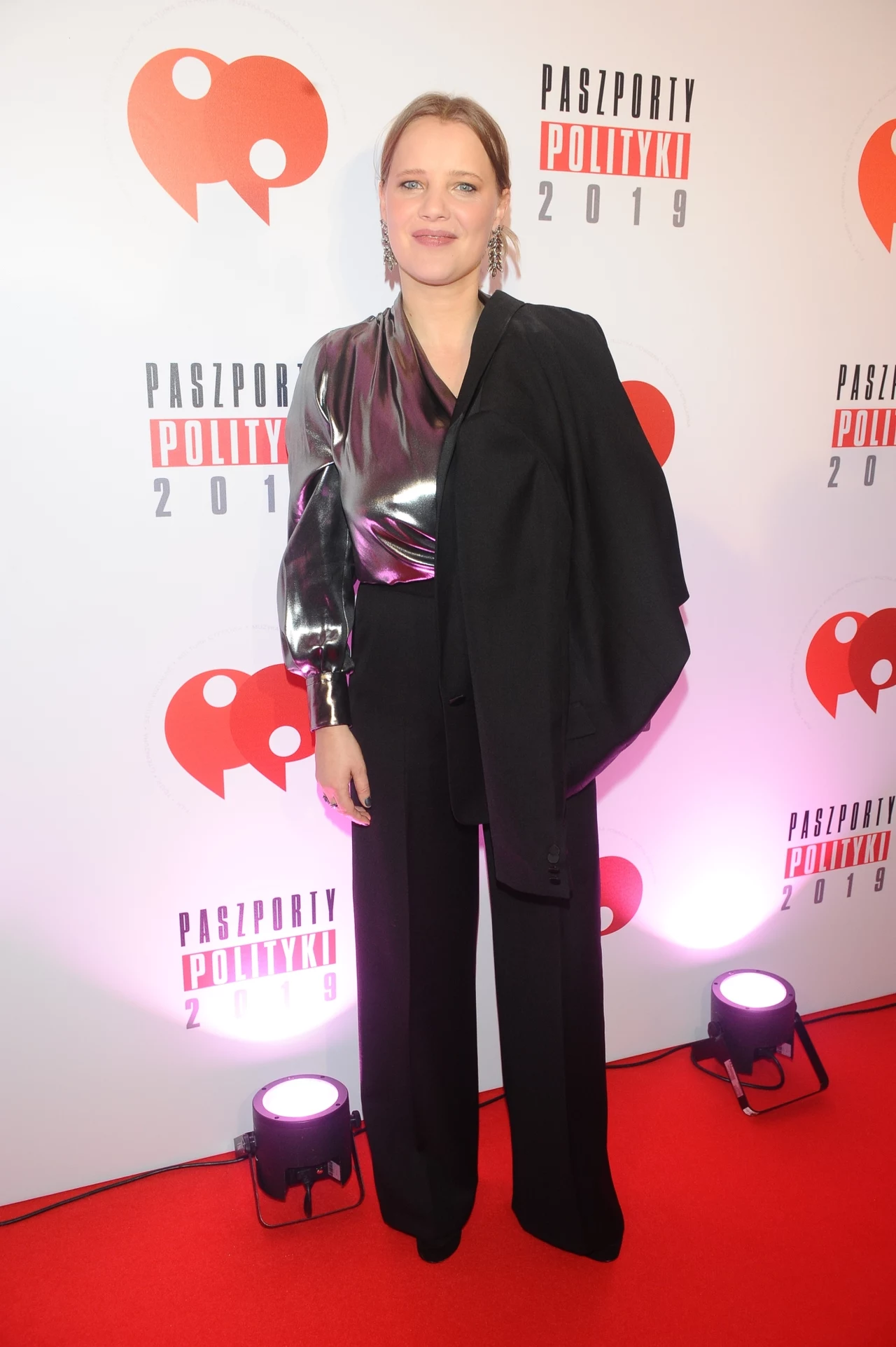 Joanna Kulig w klasycznym garniturze. Marynarka przerzucona przez ramię optycznie wydłuża sylwetkę Joanna Kulig w klasycznym garniturze. Marynarka przerzucona przez ramię optycznie wydłuża sylwetkę