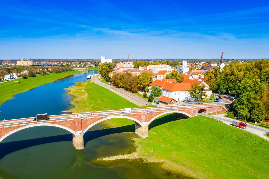 Panorama miasta Sisak z zabytkowym, kamiennym mostem na pierwszym planie