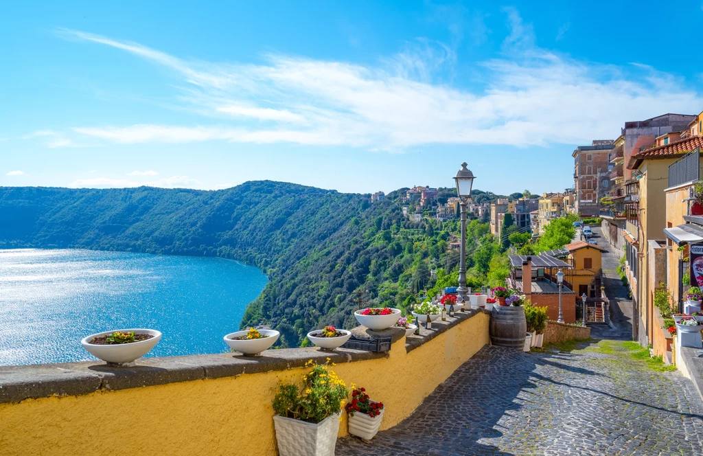 Jezioro Albano, Castel Gandolfo, Włochy Miejscowość Castel Gandolfo, słynąca z letniej rezydencji papieży, położona jest malowniczo nad kraterowym jeziorem Albano. Według Plutarcha w 406 roku p.n.e. jezioro wylało, mimo że nie padał deszcz ani nie ma ono żadnych dopływów. Przypuszcza się, że przyczyną były gazy wulkaniczne uwolnione spod osadów na dnie jeziora. Niedługo potem wybudowano tunel umożliwiający odpływ nadmiarowi wody. Jezioro Albano, Castel Gandolfo, Włochy Miejscowość Castel Gandolfo, słynąca z letniej rezydencji papieży, położona jest malowniczo nad kraterowym jeziorem Albano. Według Plutarcha w 406 roku p.n.e. jezioro wylało, mimo że nie padał deszcz ani nie ma ono żadnych dopływów. Przypuszcza się, że przyczyną były gazy wulkaniczne uwolnione spod osadów na dnie jeziora. Niedługo potem wybudowano tunel umożliwiający odpływ nadmiarowi wody.